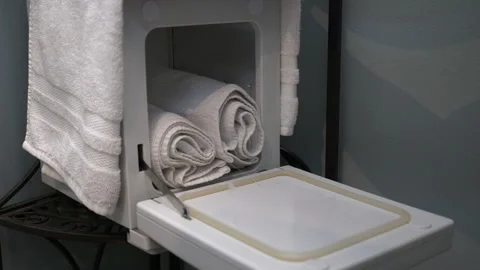 Close up of hands placing white towels in warmer at chiropractic clinic. Stock Footage 259756475