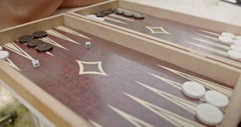 Close-up of hands playing backgammon on a detailed wooden board, highlighting 스톡 동영상 280572629