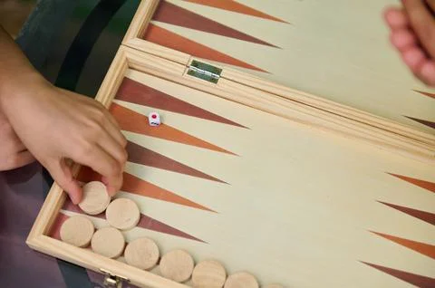 Close-up of hands playing a backgammon game with wooden pieces and a dice Stock Photos