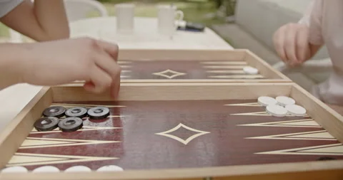 Close-up of hands playing backgammon on a wooden board with checkers pieces Stock Footage 280573143