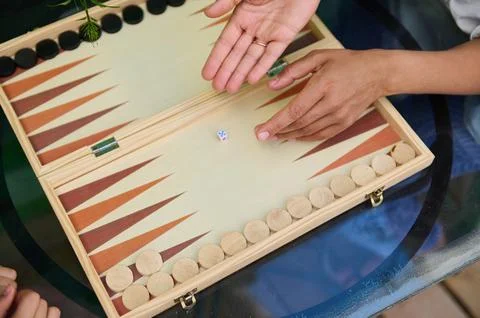 Close-up of hands playing backgammon on wooden board game outdoors Stock Photos