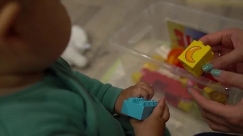 Close up of hands playing with colorful interlocking plastic bricks of meccano Stock Footage 80130137
