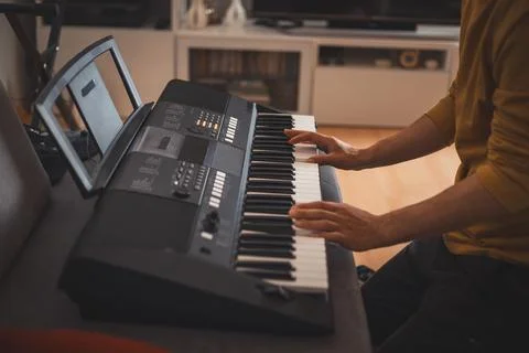 Close-up of hands playing a digital keyboard under warm natural light, captur Fotos Stock