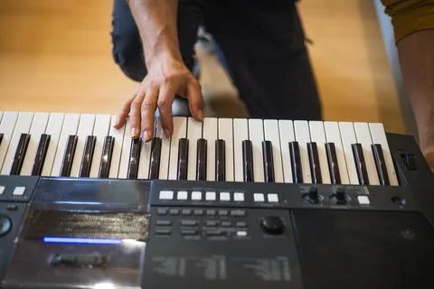 Close-up of hands playing a digital keyboard under warm natural light, captur Foto stock