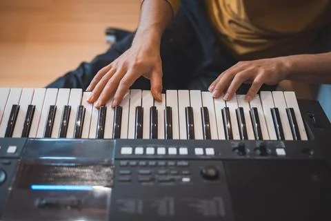 Close-up of hands playing a digital keyboard under warm natural light, captur Foto stock