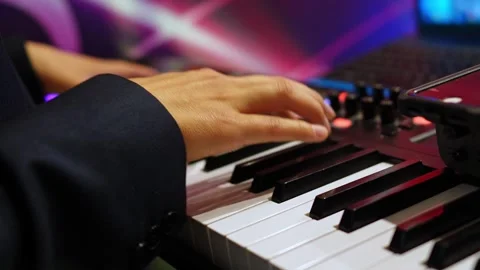 Close-up of hands playing electronic keyboard with colorful lights Stockbeeldmateriaal 315896107
