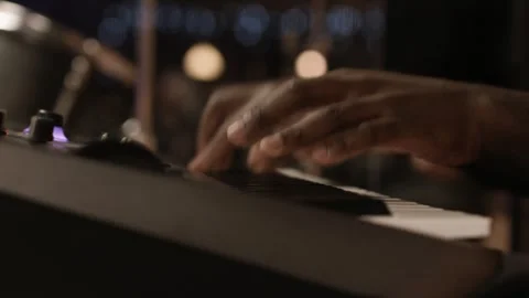 Close-up of hands playing fast keyboard passage, drummer visible in background Stock Footage 345096285