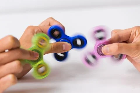 Close up of hands playing with fidget spinners Stock Photos