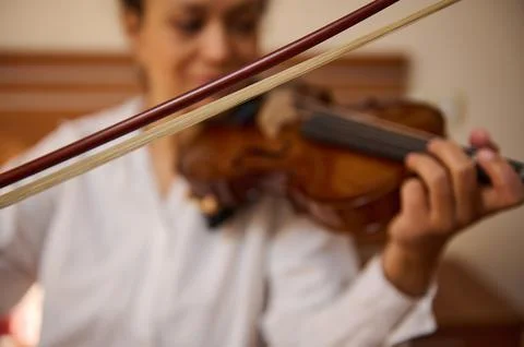 Close-up of hands playing a violin with focus on the strings and bow Stock Photos