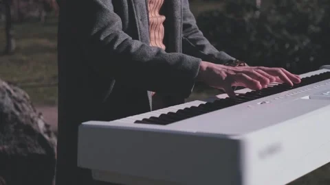 Close up of hands playing white digital piano in cinematic outdoor light Stock Footage 334629174