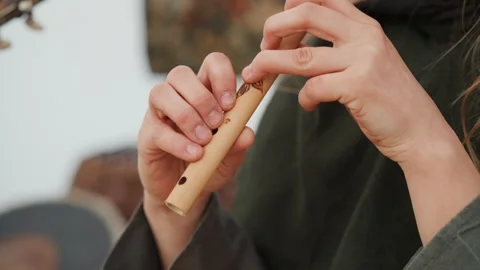Close-up hands playing wooden flute with finger movement under warm natural Stock Footage 345676370