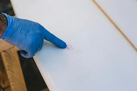 Close up of hands pointing out the damaged part to repair on a surfboard Foto stock