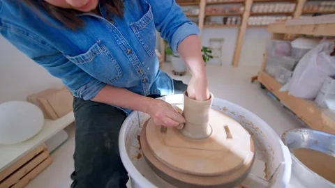 Close up of hands in pottery studio shaping clay mug on pottery wheel Stock Footage 221949704