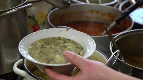Close-up. hands pour the soup from the pan into the plate. Stock Footage 131760300