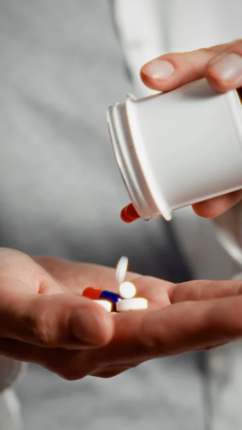Close up of hands pouring capsules from container into palm for medication p Stock Footage 331538505