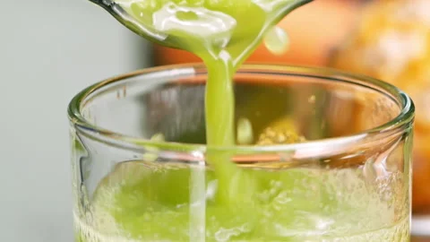 Close-up of hands pouring green leaf salad Kale smoothie into a glass. Stock Footage 157408880