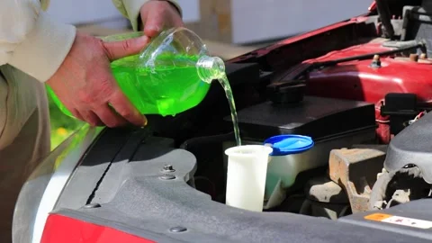 Close-up of hands pouring summer windshield washer fluid into reservoir under Stock Footage 334043384