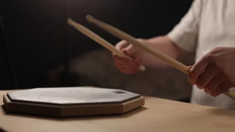 Close-up of hands practicing drumming on a practice pad with sticks Stockbeeldmateriaal 341737458