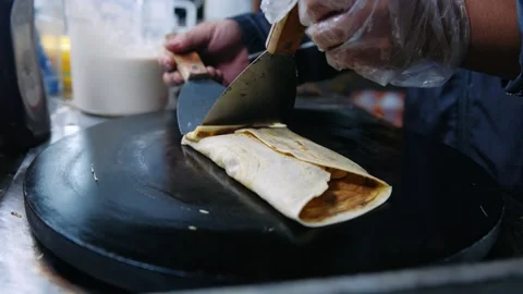 Close up of hands preparing a chocolate banana crepe on a hot plate at a ni.. Stock Footage 336981818