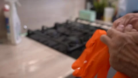 A Close-Up of Hands Preparing to Don Bright Orange Gloves, Emphasizing the Stock Footage 321051302