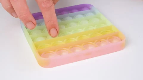 Close-up of hands pressing colorful pop it fidget toy Stockbeeldmateriaal 339620664