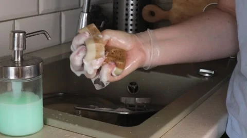 Close-up of hands pressing a saturated sponge filled with detergent, releas.. Stock Footage 320737885