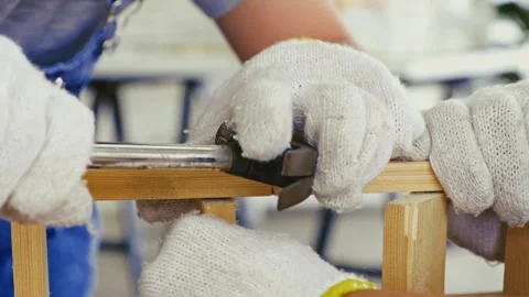 Close-up of hands in protective gloves hammering a nail into wood Stock Footage 314648551