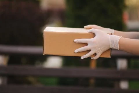 Close up hands in protective gloves hold parcel. Delivery dervise bring order to Stock Photos