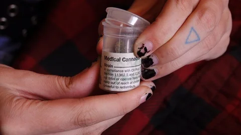 Close up of hands pulling cannabis bud from a medical cannabis container Stock Footage 118938331