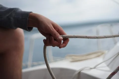Close up of hands pulling a rope, sheet on a sailboat Stock Photos
