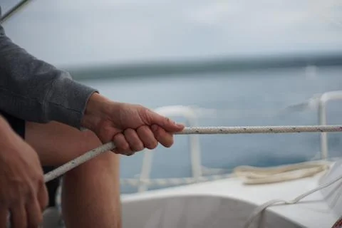 Close up of hands pulling a rope, sheet on a sailboat Stock Photos