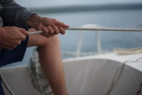 Close up of hands pulling a rope, sheet on a sailboat Stock Photos