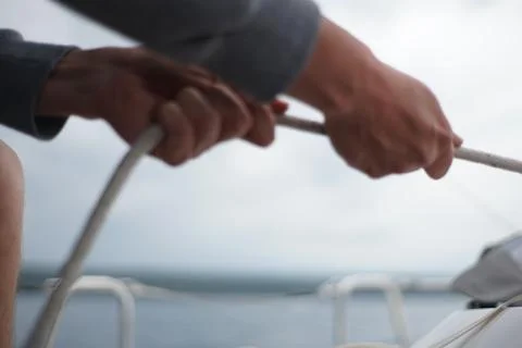 Close up of hands pulling a rope, sheet on a sailboat Stock Photos