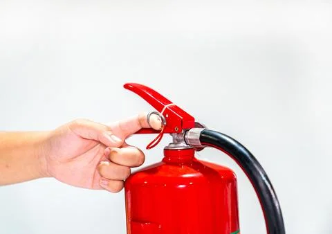 Close up hands pulling safety pin of fire extinguisher. Stock Photos