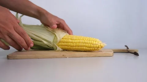 Close up hands put open corn on the cob isolated on white background  Stock Footage 243127791