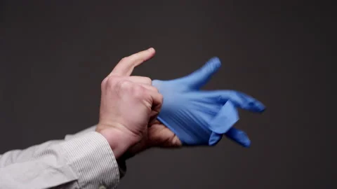 Close up of hands putting on blue latex gloves on a dark backdrop Video stock 134263672