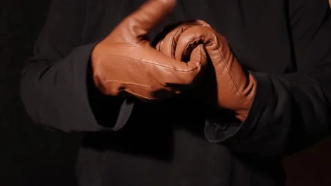 Close-up of hands putting on brown leather gloves in a dark setting Stock Footage 339175314