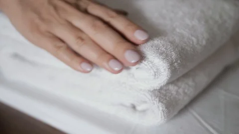 Close-up of hands putting stack of fresh white bath towels on the bed sheet Stock Footage 103203718