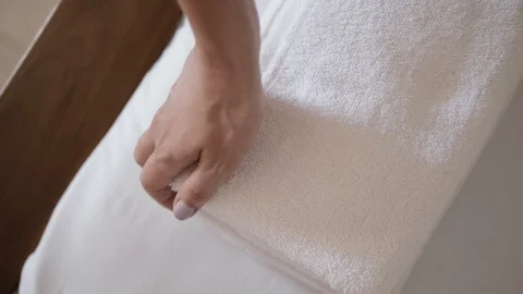 Close-up of hands putting stack of fresh white bath towels on the bed sheet Stock Footage 103203767