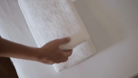 Close-up of hands putting stack of fresh white bath towels on the bed sheet Stock Footage 103203844