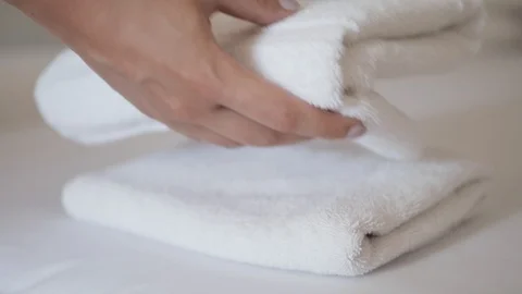 Close-up of hands putting stack of fresh white bath towels on the bed sheet Stock Footage 103245630