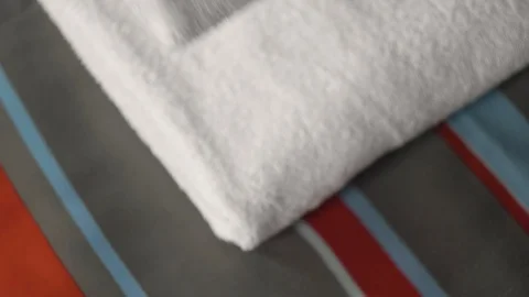 Close-up of hands putting stack of fresh white bath towels on the bed sheet Stock Footage 123804490