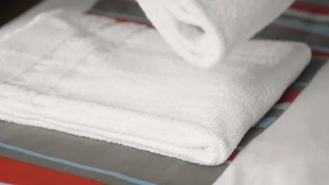 Close-up of hands putting stack of fresh white bath towels on the bed sheet Stock Footage 123804647
