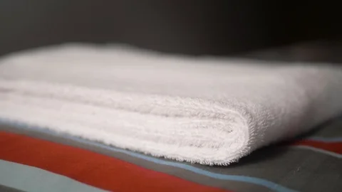 Close-up of hands putting stack of fresh white bath towels on the bed sheet Stock Footage 124204645