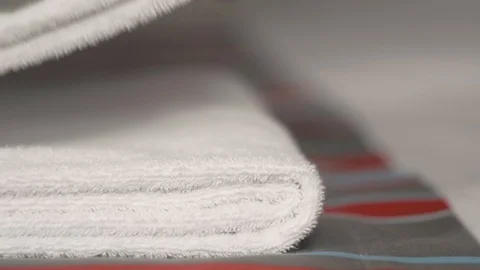 Close-up of hands putting stack of fresh white bath towels on the bed sheet Stock Footage 124204718