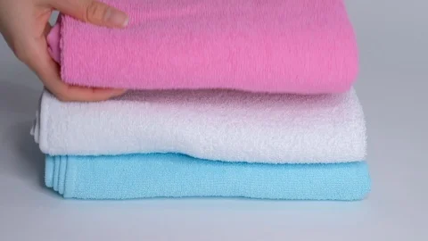 Close-up of hands putting stack of fresh bath towels on the bed sheet. Room Stock Footage 124204964