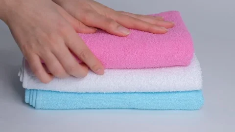 Close-up of hands putting stack of fresh bath towels on the bed sheet. Room Stock Footage 124327368