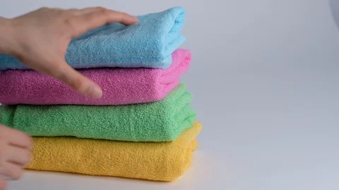 Close-up of hands putting stack of fresh bath towels on the bed sheet. Room Stock Footage 124526659