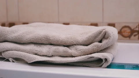 Close-up of hands putting stack of fresh white bath towels on the bed sheet Stock Footage 141449084
