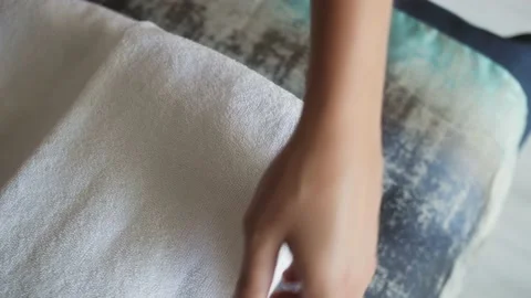 Close-up of hands putting stack of fresh white bath towels on the bed in hotel Stock Footage 219479996